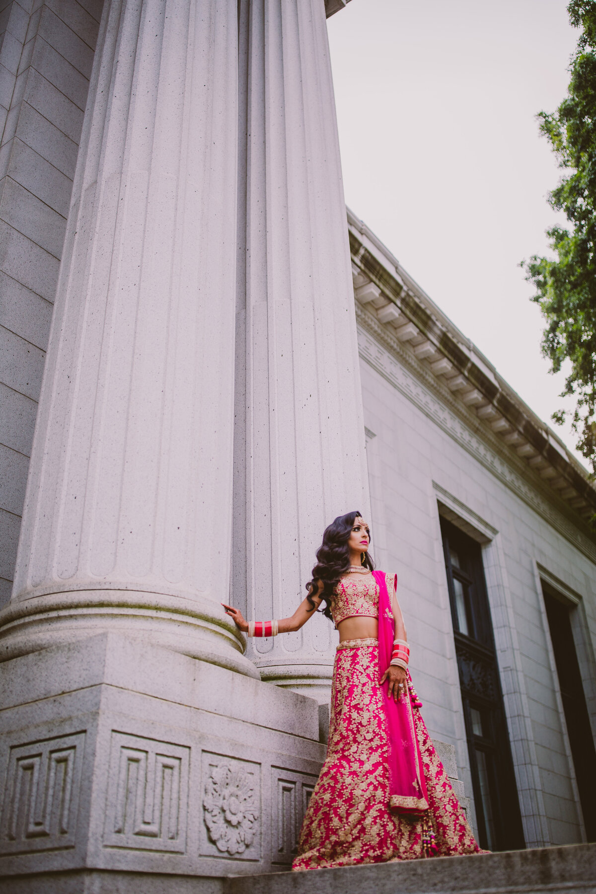 A sikh bride standing in front of white columns on her wedding day outside building in hartford connecticut
