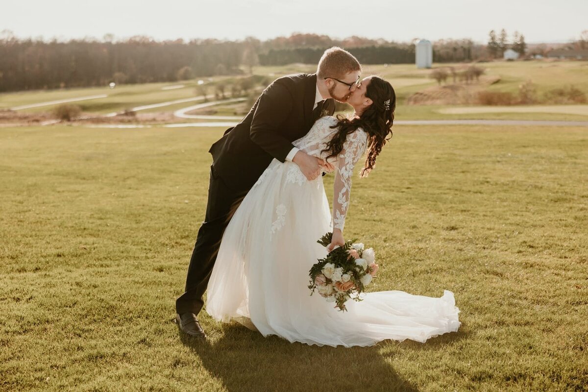 Newlyweds sharing a kiss on a scenic Hudson Valley golf course, captured by a Hudson Valley wedding photographer.