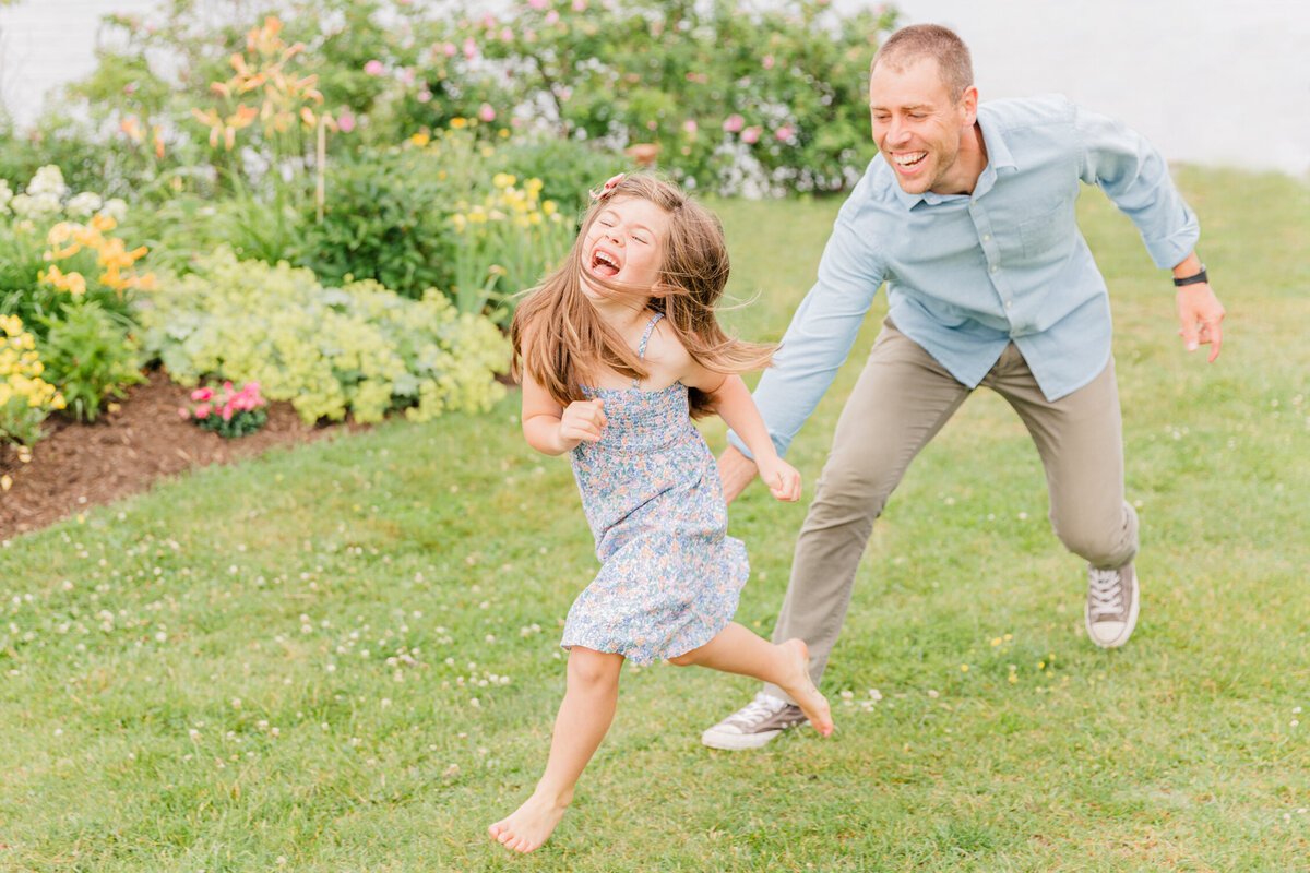 Dad chasing laughing daughter through a lush green park