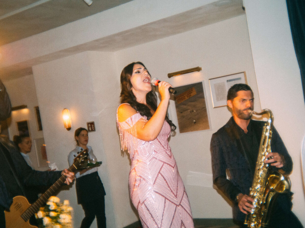 Wedding vocalist singing in sparkling black gown under spotlight

