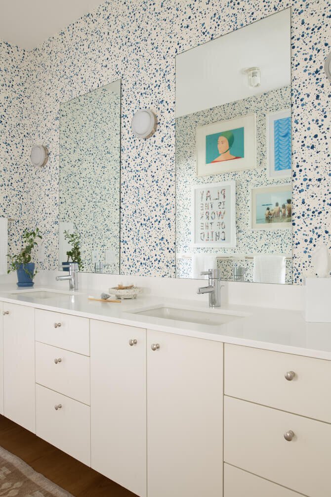 Kid-friendly bathroom designer in Hingham, Massachusetts, designs a new construction home bath with a white vanity, fun wallpaper, and bright, colorful art.