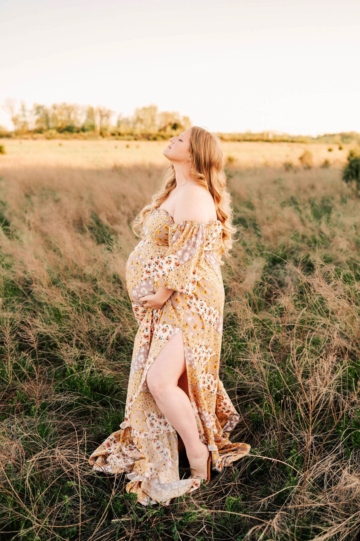 pregnant mom with red hair in floral dress relaxing during Springfield MO maternity photography session