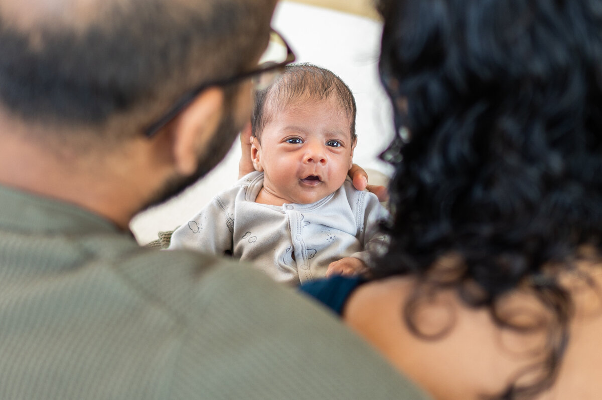 baby smiling at parents in a home newborn session 