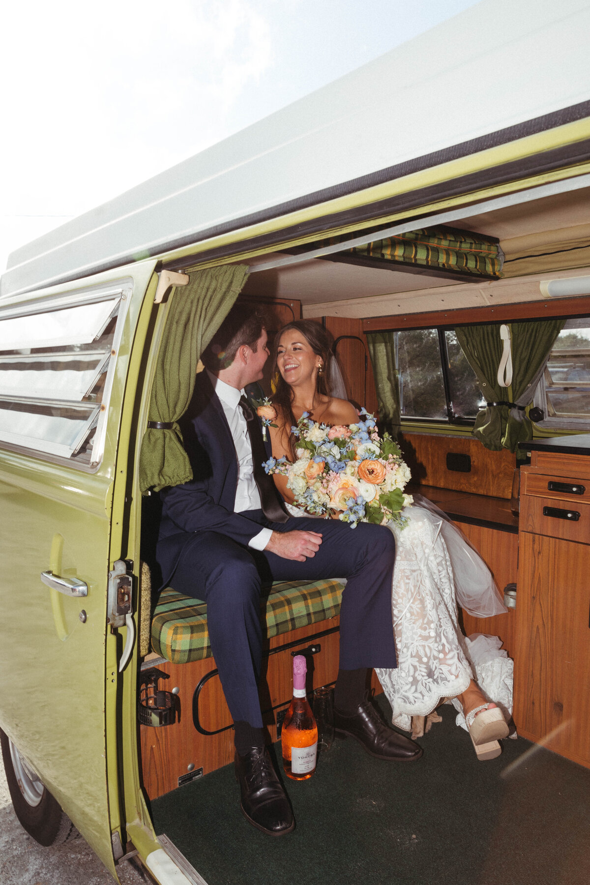 Bride and Groom sitting in back seat with floral bouquet