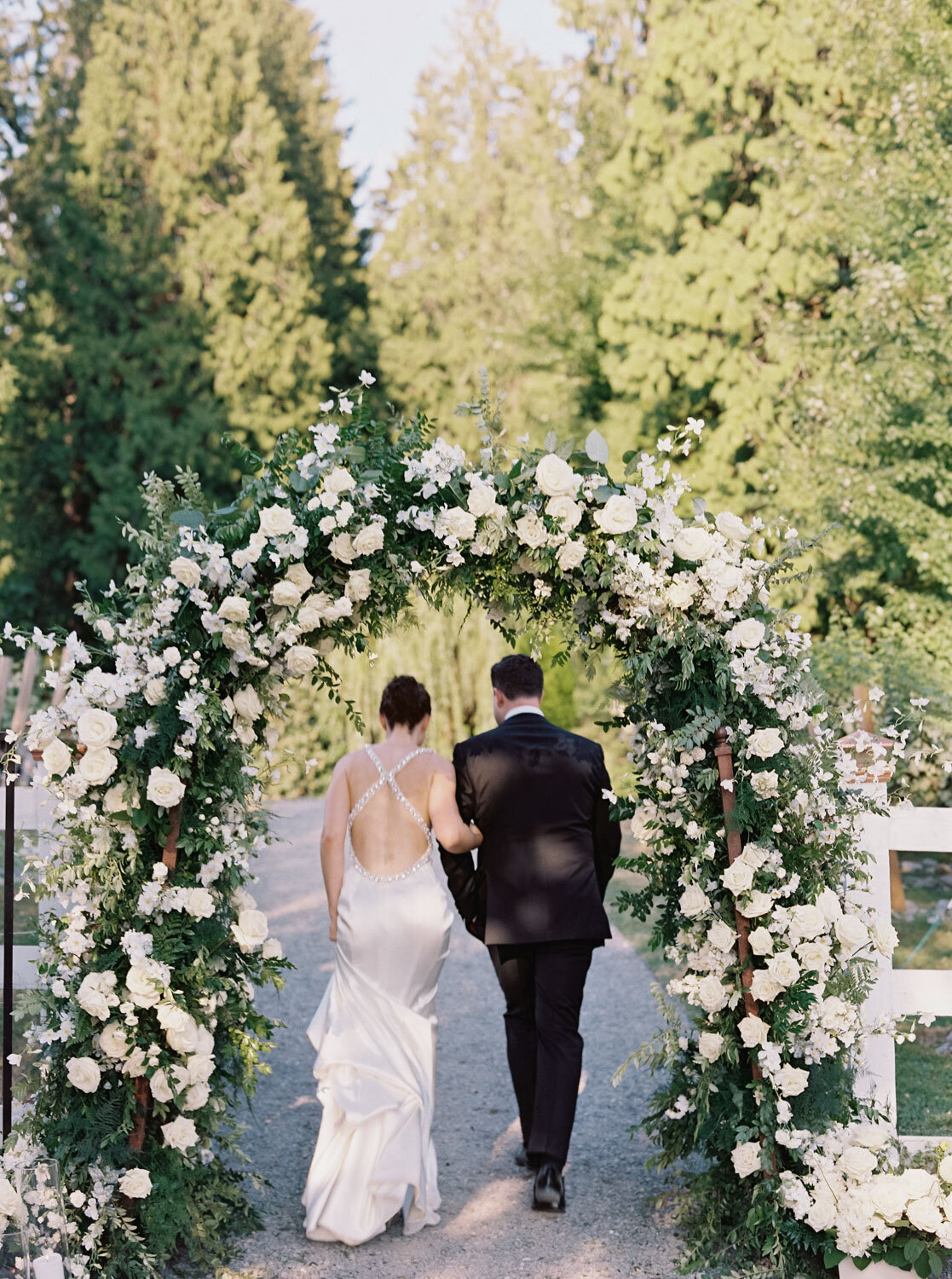 Bride and groom walking under a floral arch