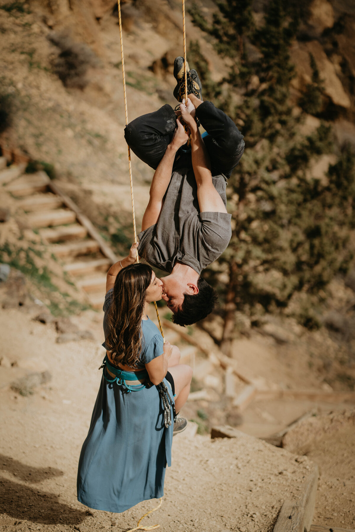 Couple kissing while rock climbing during engagement photos at Smith Rock State Park