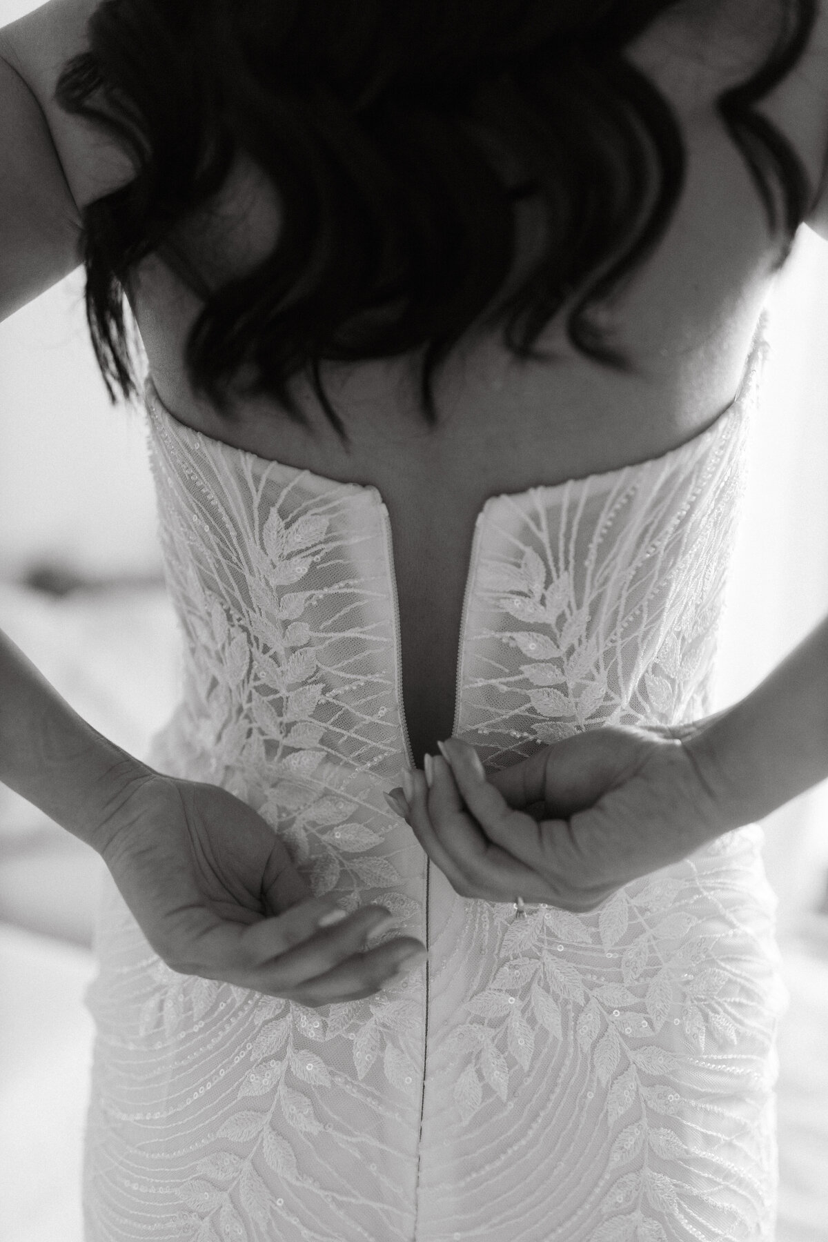 Wedding Photographer & Videographer, black and white image of bride clasping the back of her dress closed