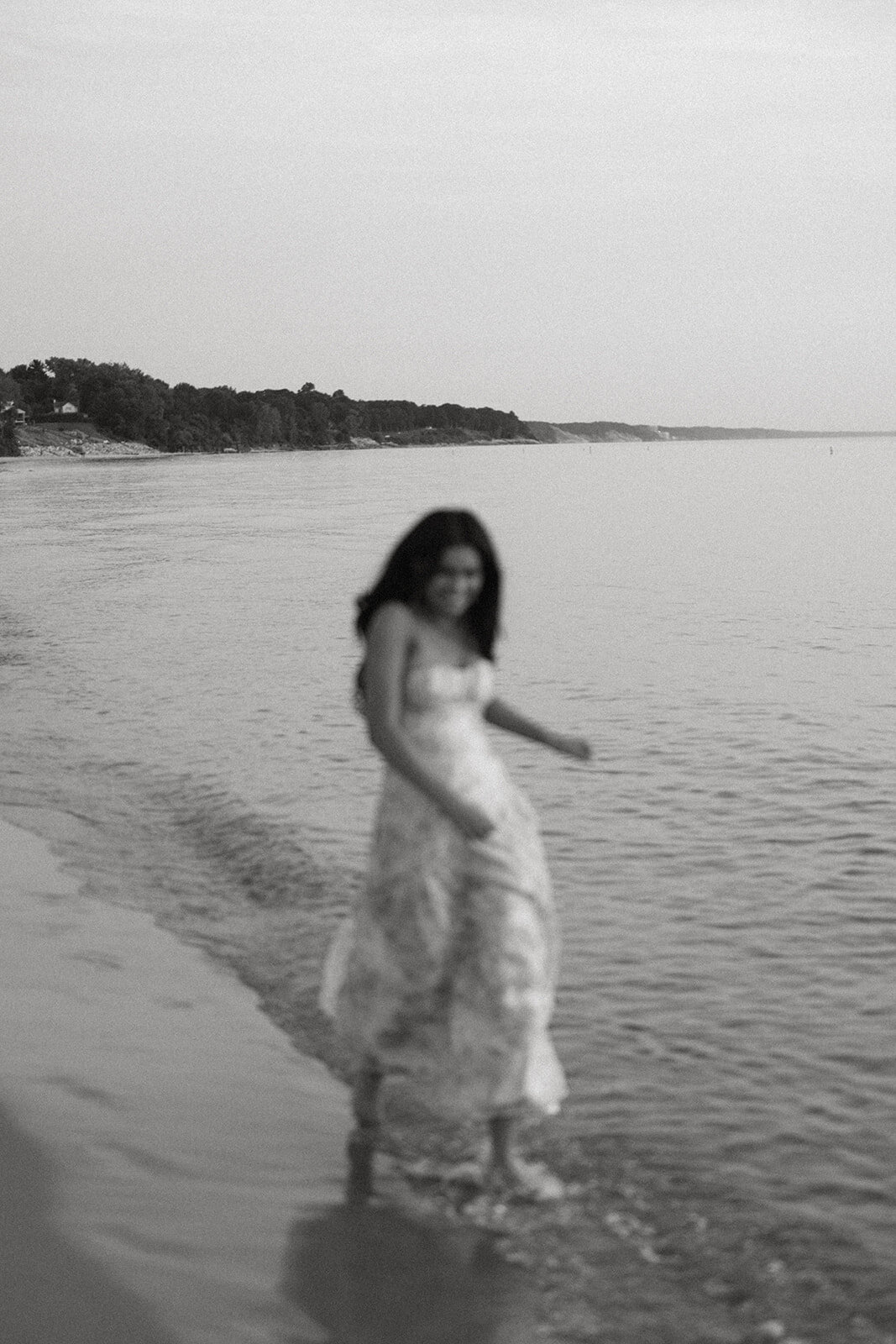 Artistic black and white motion photo of senior walking through Lake Michigan water during her South Haven senior photoshoot.
