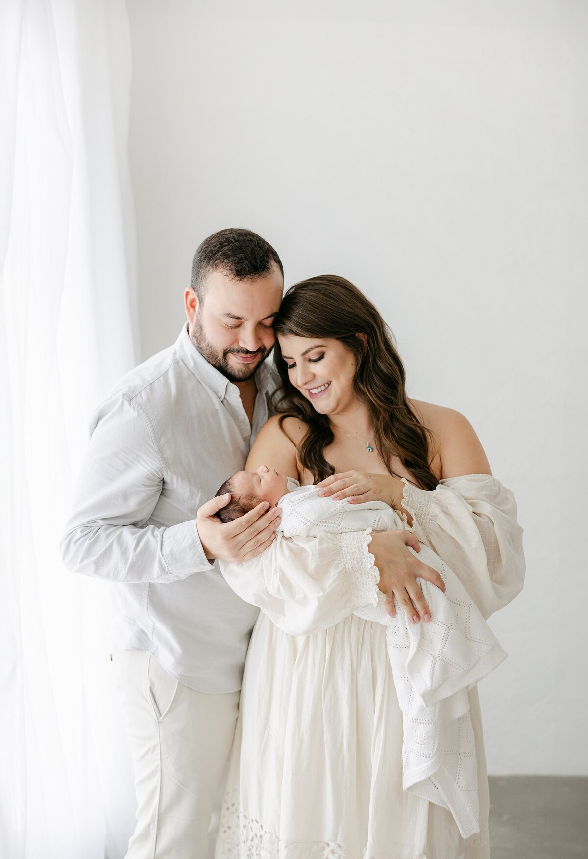 new mom and dad holding baby in studio