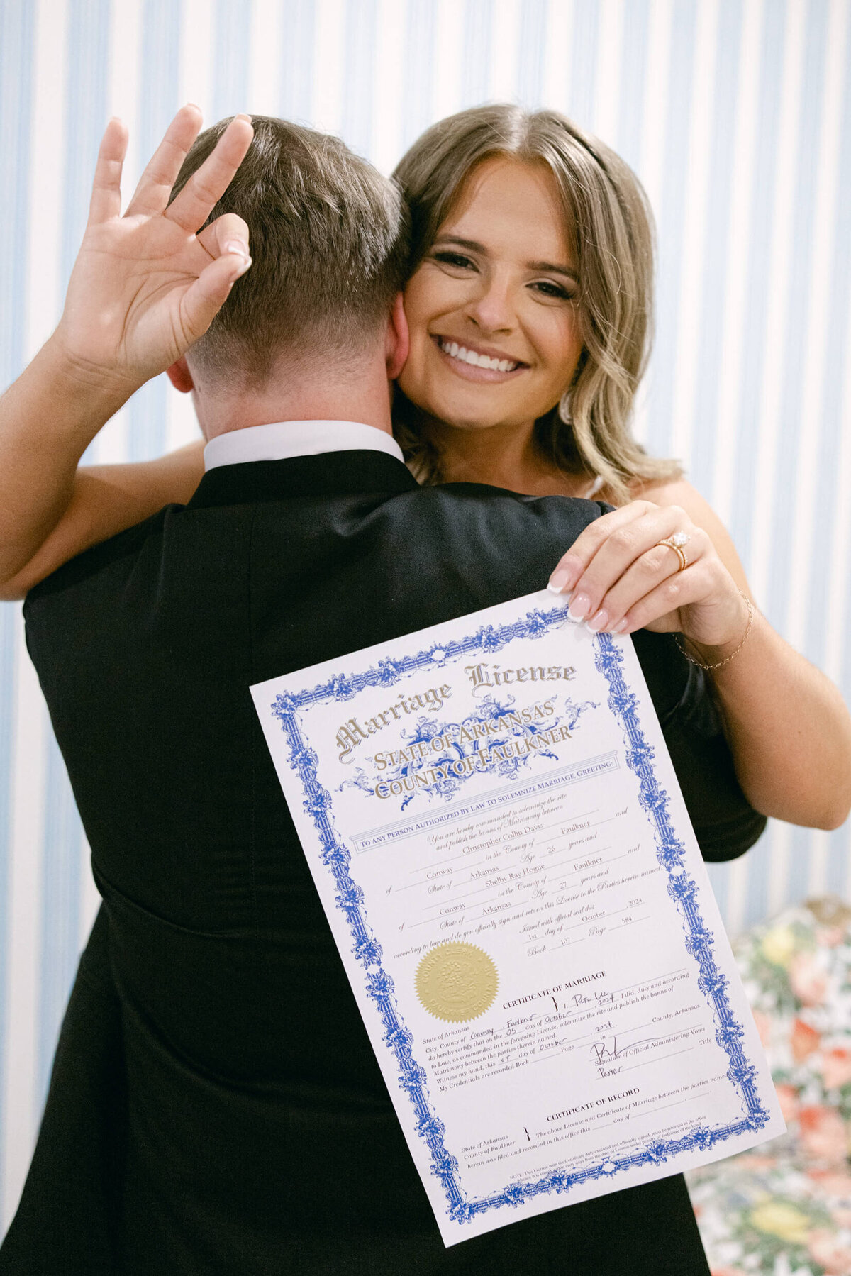 A wedding photo of the bride smiling while she holdes her marriage license