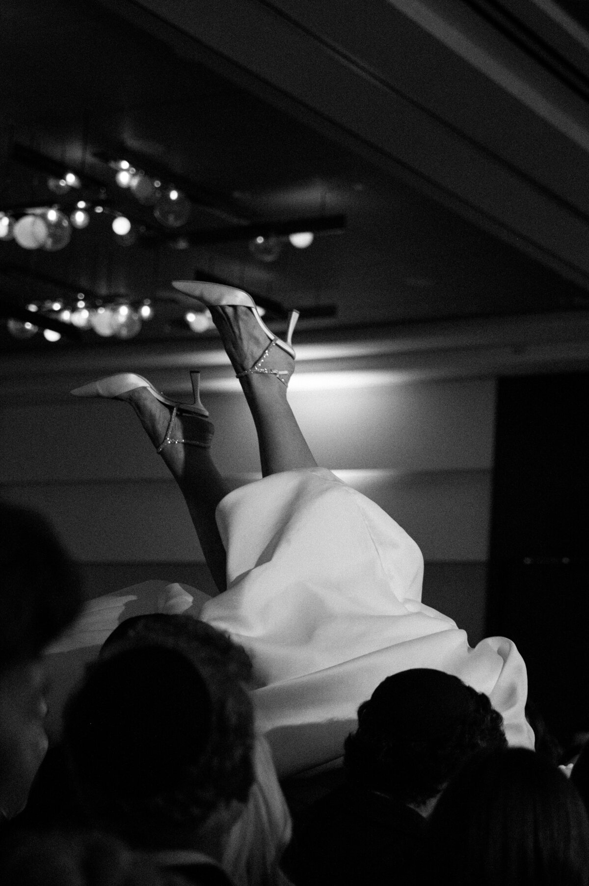 Monochrome photo showing bride lifted by guests at Toronto Jewish wedding.