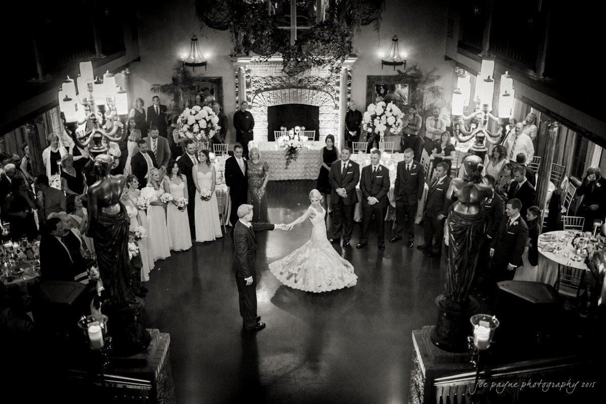 A bride and groom dancing surrounded by guests.