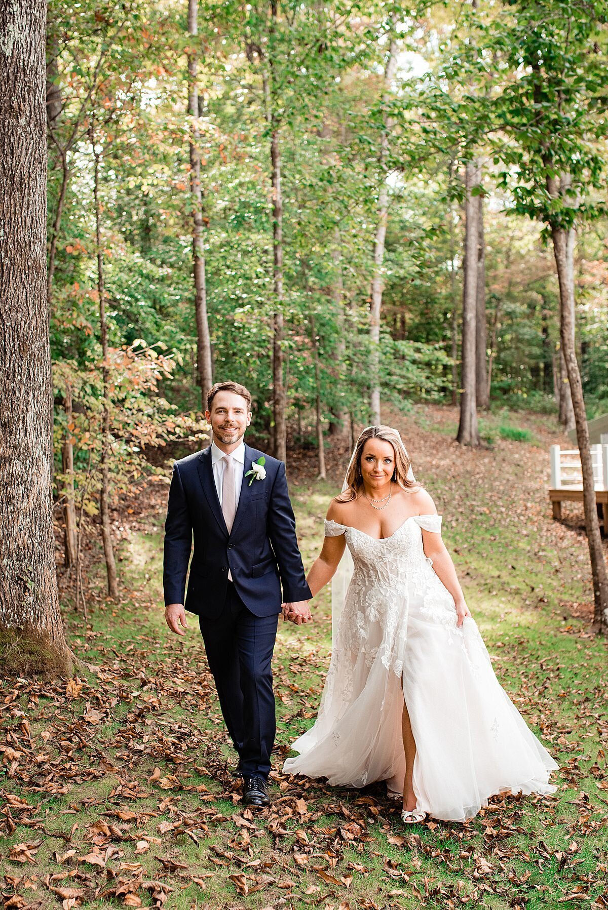 Couple walking hand and hand outside after ceremony with fall foliage around them