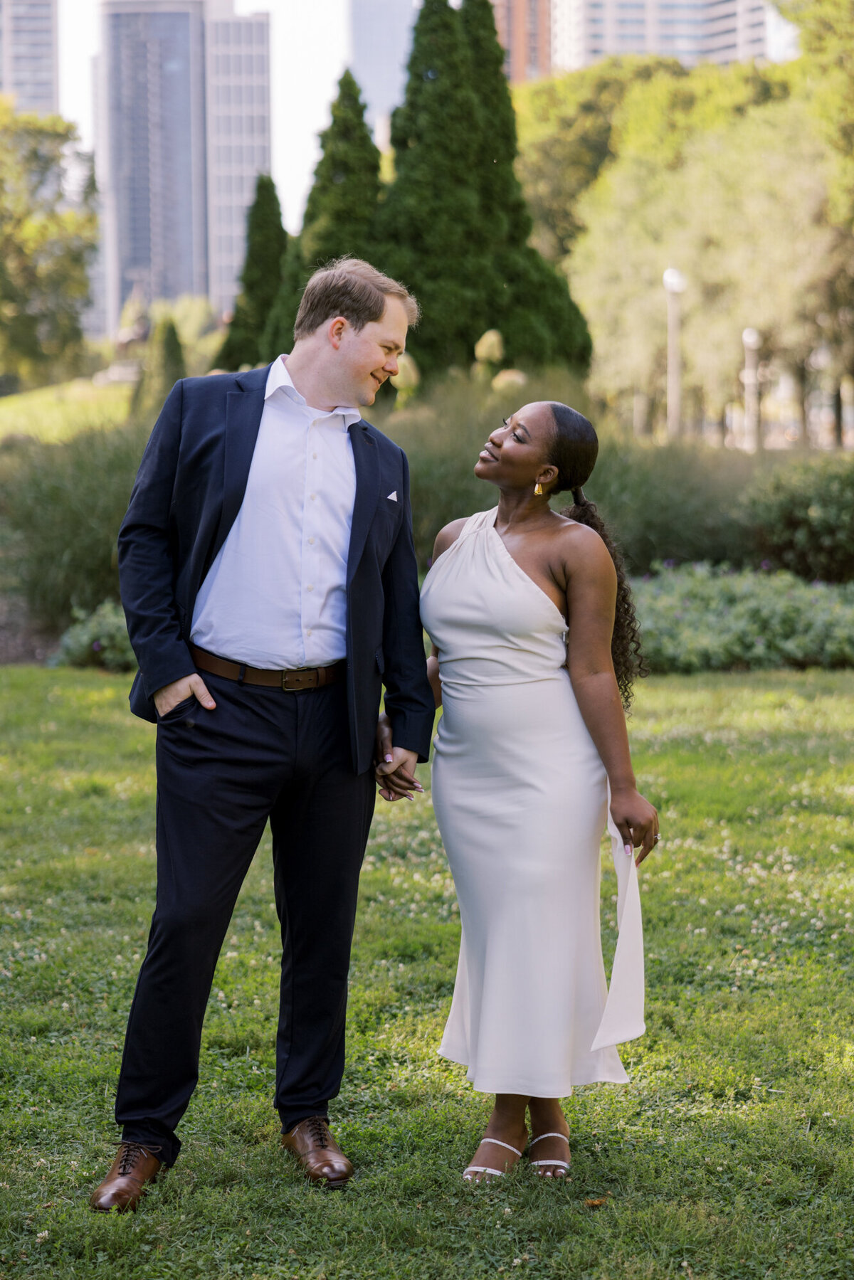 A couple shares a romantic moment in a formal garden along Michigan Avenue, surrounded by lush greenery and city charm.