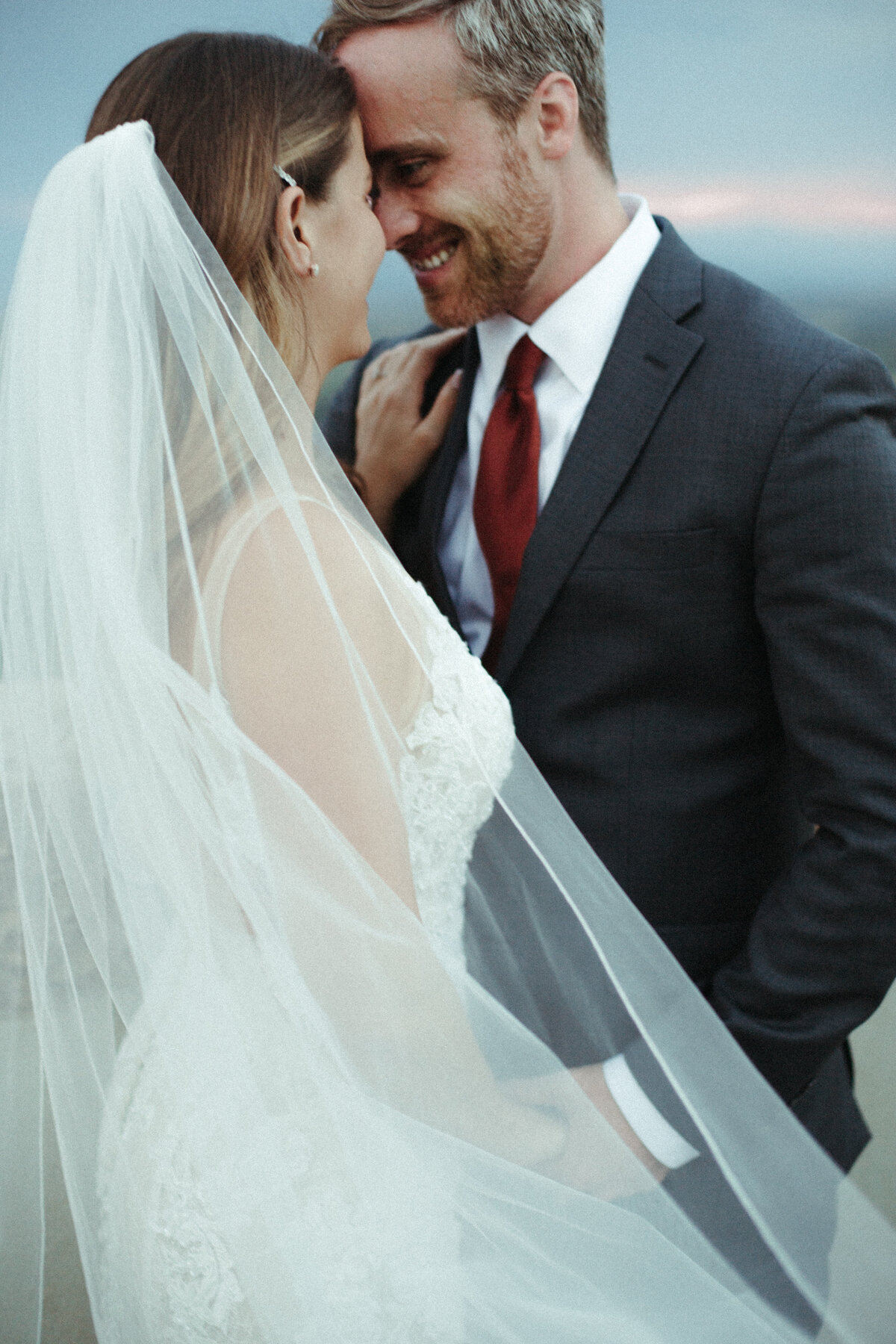 Bride and groom on their wedding day behind the bride's veil.
