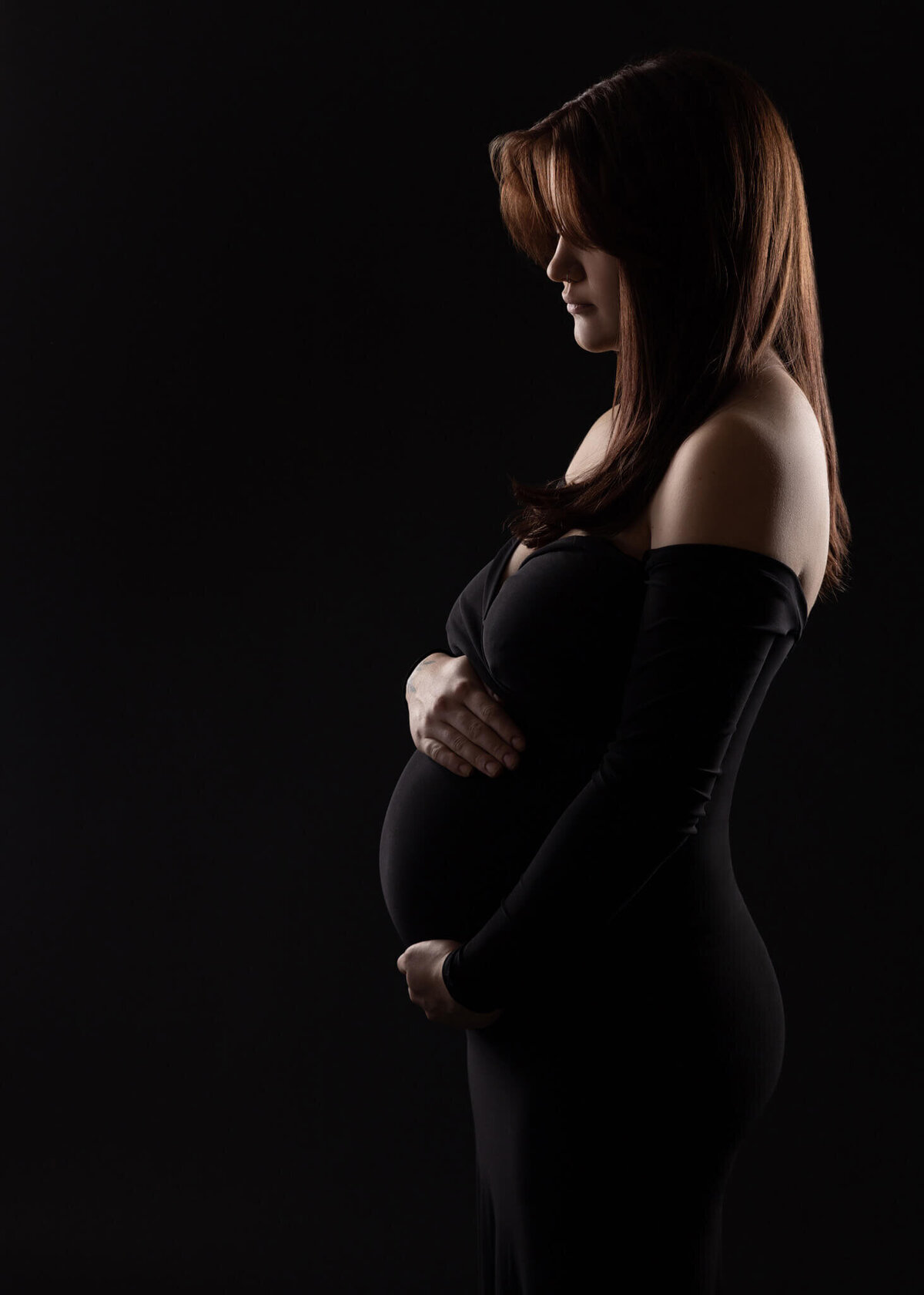 silhouette of a pregnant woman holding her belly wearing a black dress