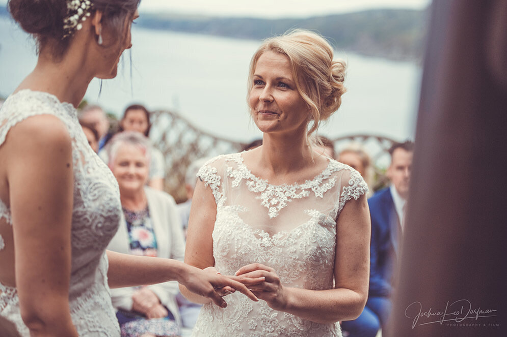 One bride is putting the wedding ring on the other bride