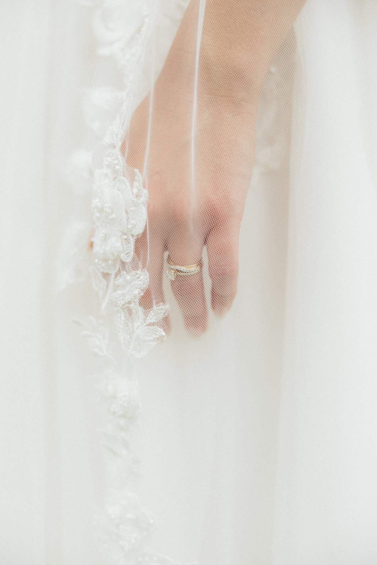 The bride showing off her wedding ring under her veil.