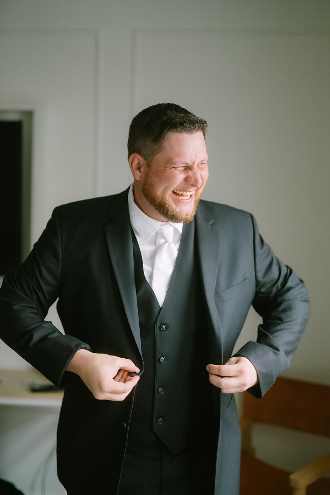 Groom putting on black suit