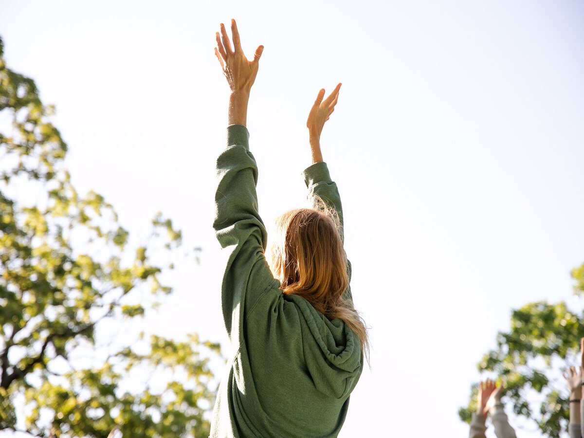 A woman reaches up to the sky in a yoga pose during group yoga at a Rising Ridge retreat. 