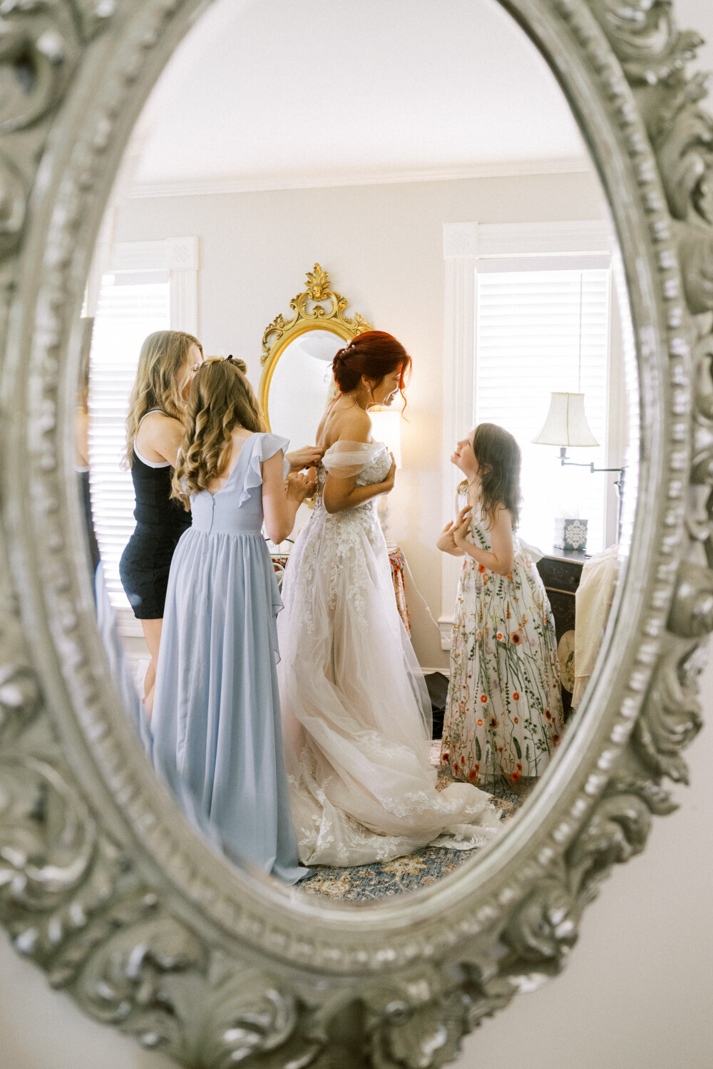 reflection-of-bride-getting-ready-with-daughters-in-oval-mirror