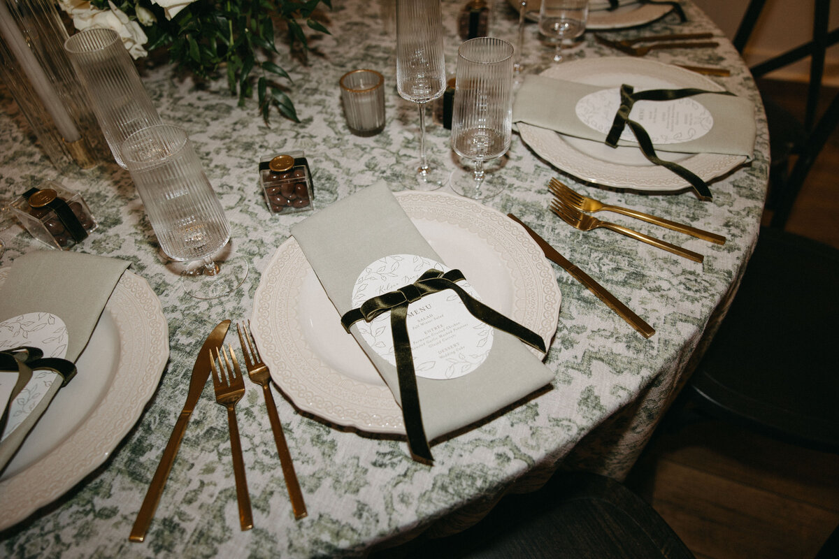 table decor at wedding with silverware plates and green accents