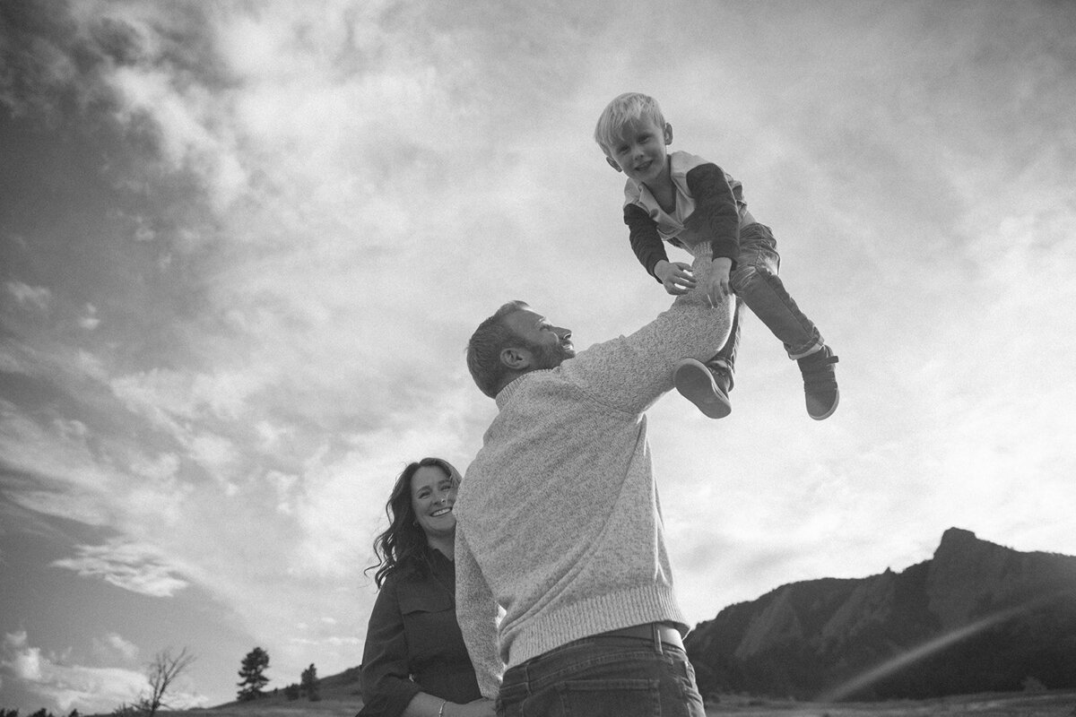 father holds sun to the sky while family looks at him and he laughs