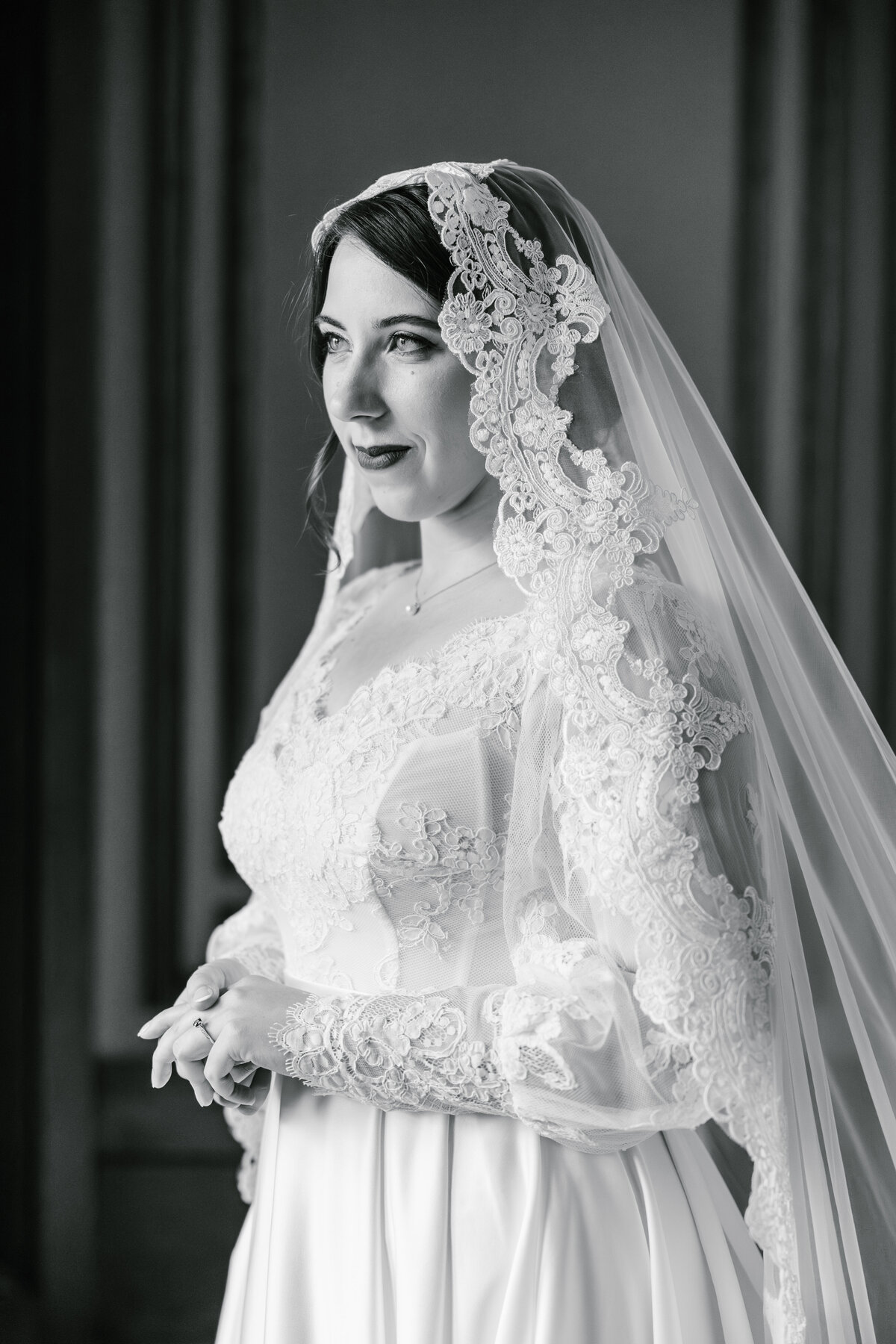 Black and white portrait of a bride looking to the side wearing a lace veil