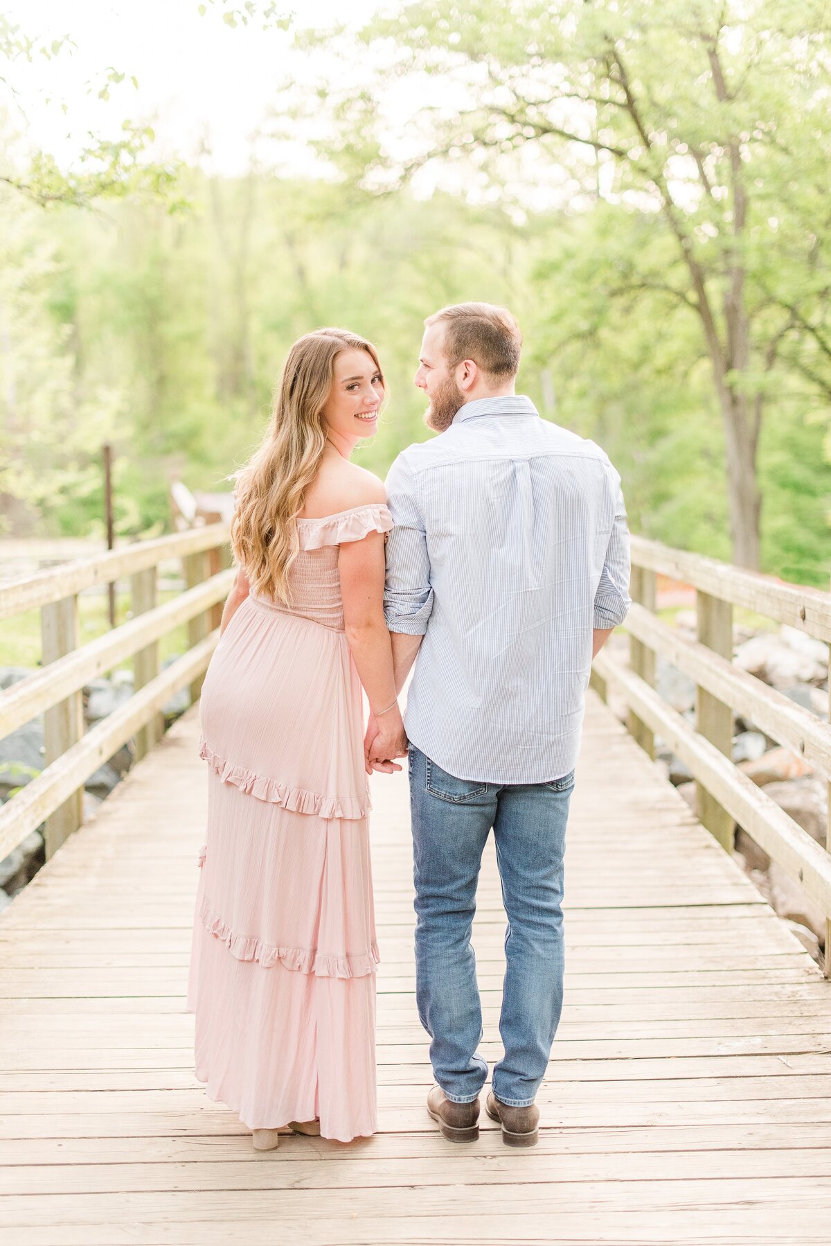 couple hugging on bridge pink maxidress and blue button up shirt