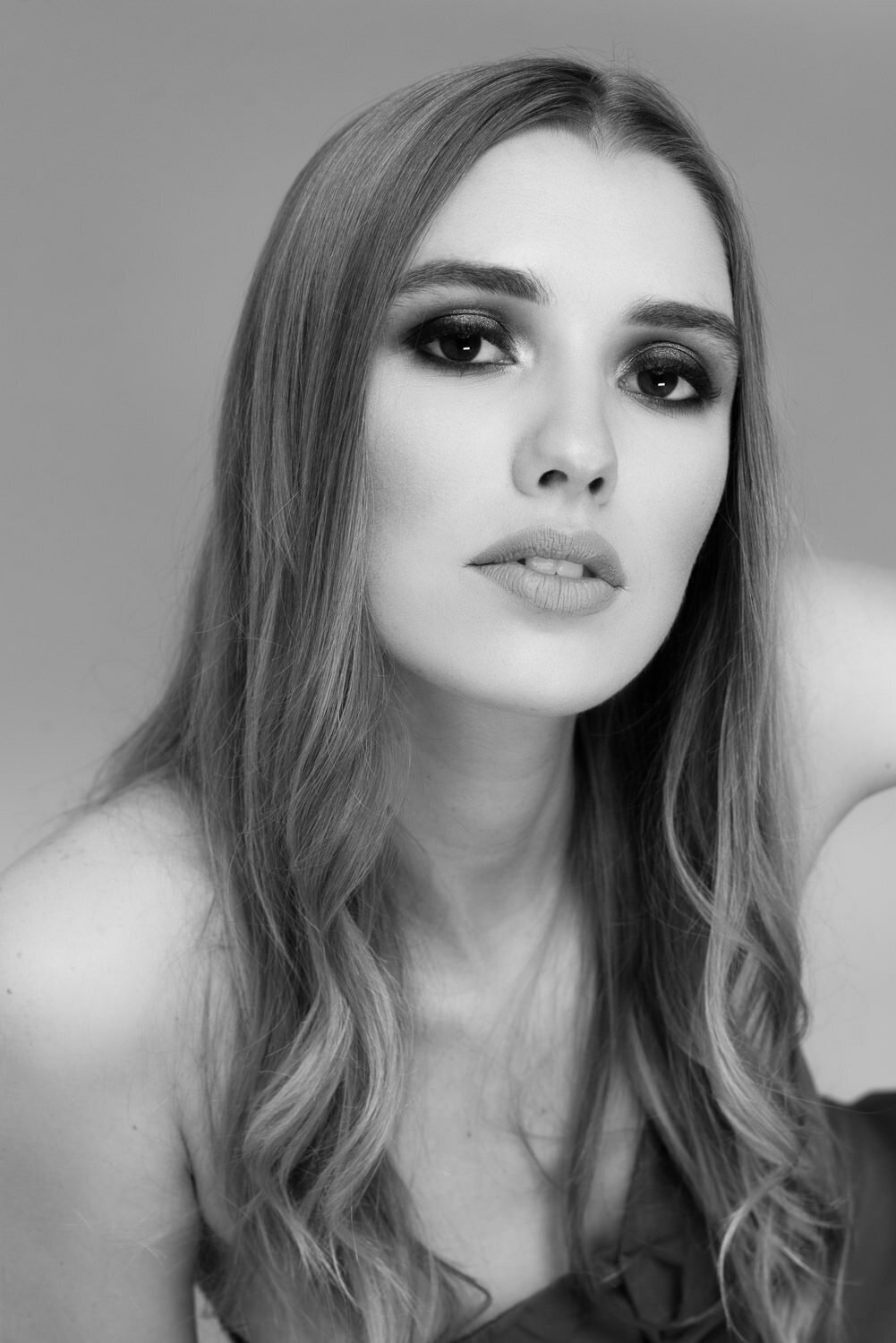 Simple and refined beauty portrait of a woman in studio, featuring minimal styling and an editorial feel.