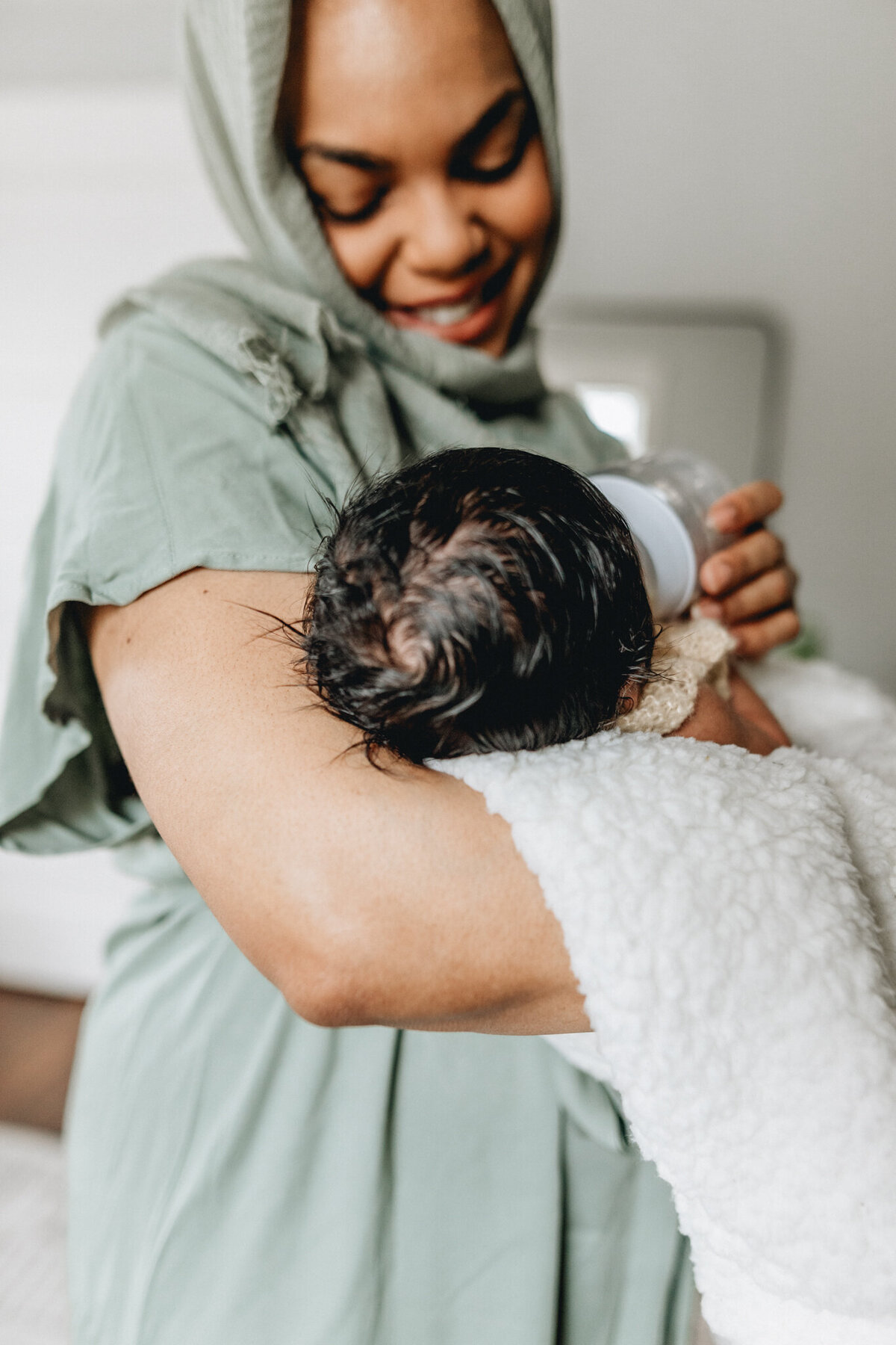 Newborn photo with a mom feeds and snuggles newborn