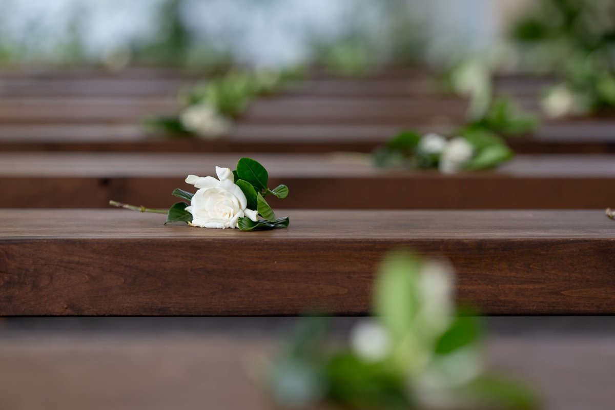 White gardenias on wooden benches for each guest at wedding ceremony
