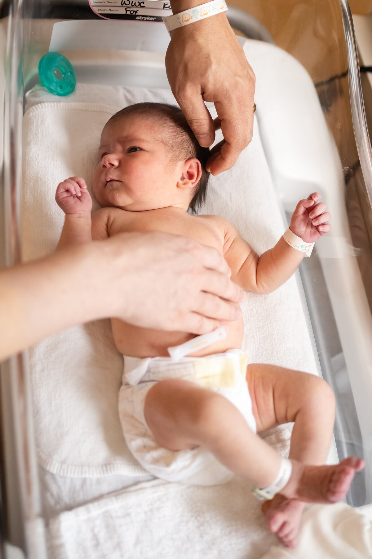 Newborn baby in diaper laying in bassinet