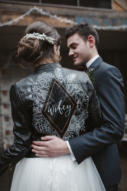 wedding couple with bride wearing black leather jacket and botanical and pomegranate painted design