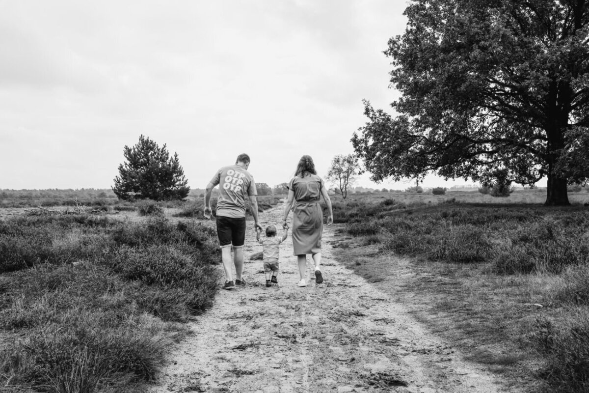Zwart-wit foto van een gezin dat over een pad loopt in een heideveld.