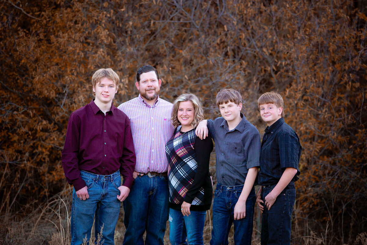 Family standing in fall colored trees