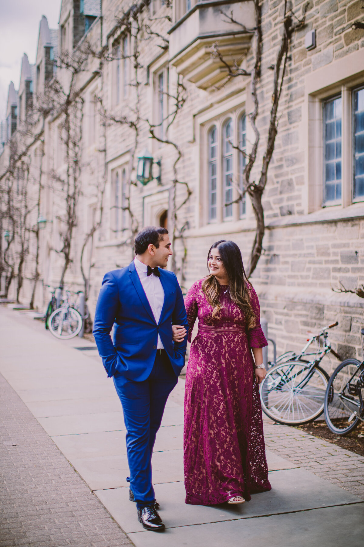 An engaged couple walking through princeton university in the winter with bicycles in the back