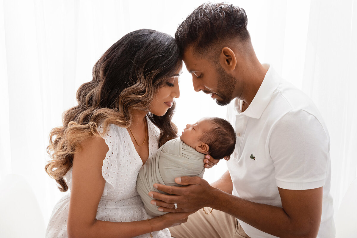 Parents holding their newborn in a warm, intimate family portrait