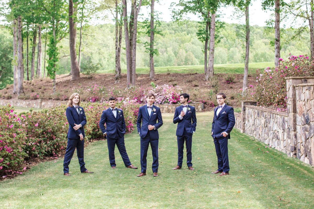 groomsmen stand in various positions among azaleas by Texas photographer
