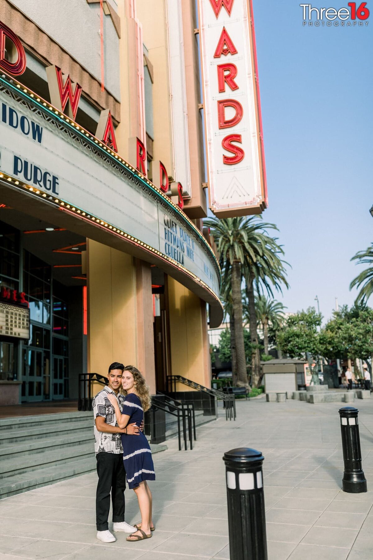 Engaged couple embrace each other as they pose for photos in front of the movie theater in Downtown Brea
