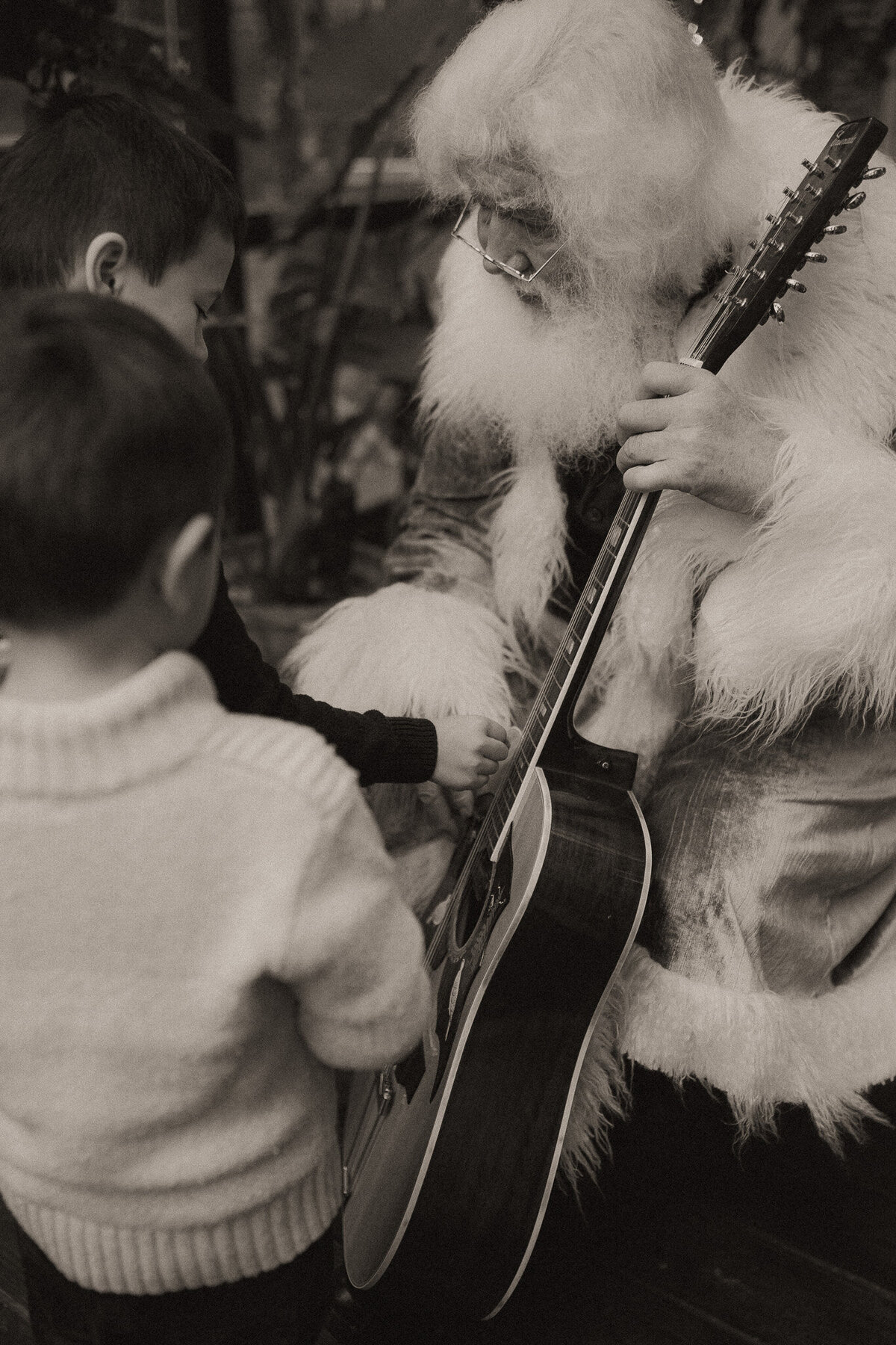 Santa showing two children his cool guitar. 