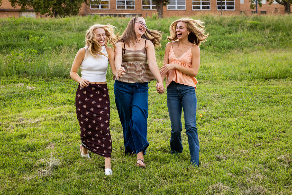 MBP Senior Team walking in a grass field hand in hand laughing in Lawrence, KS