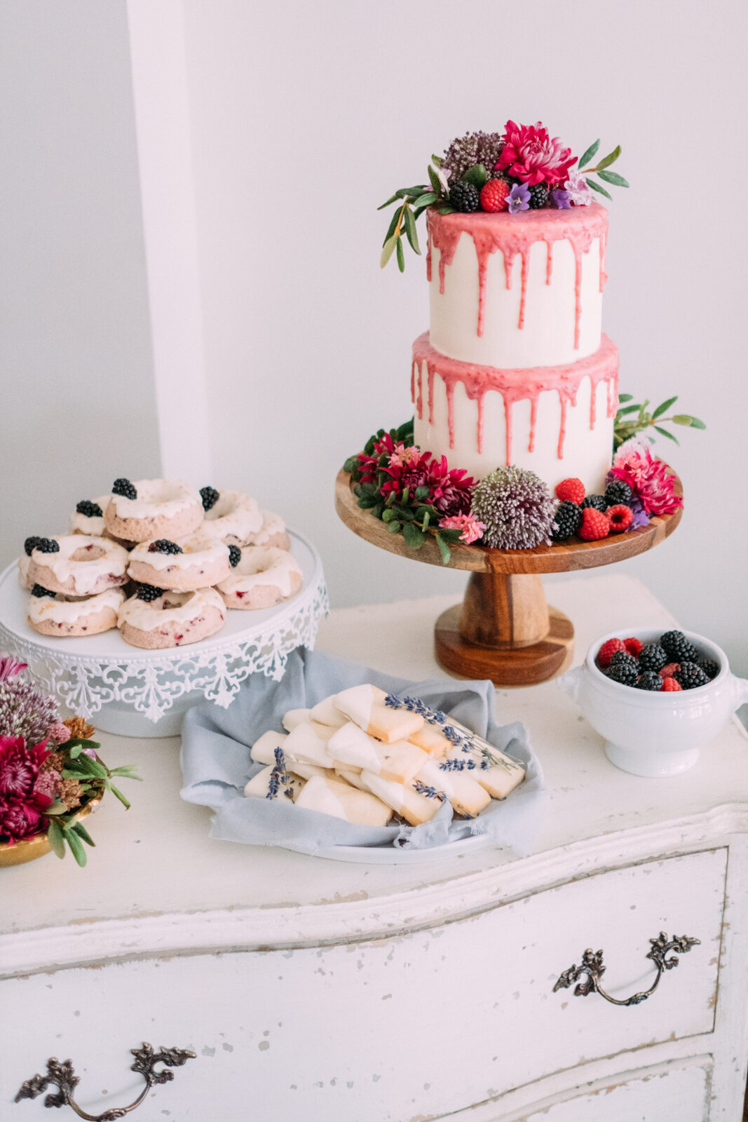 Two-tiered white and pink drip wedding cake, topped with vibrant florals, created by Bake My Day, contemporary cakes & desserts in Calgary, Alberta, featured on the Brontë Bride Vendor Guide.