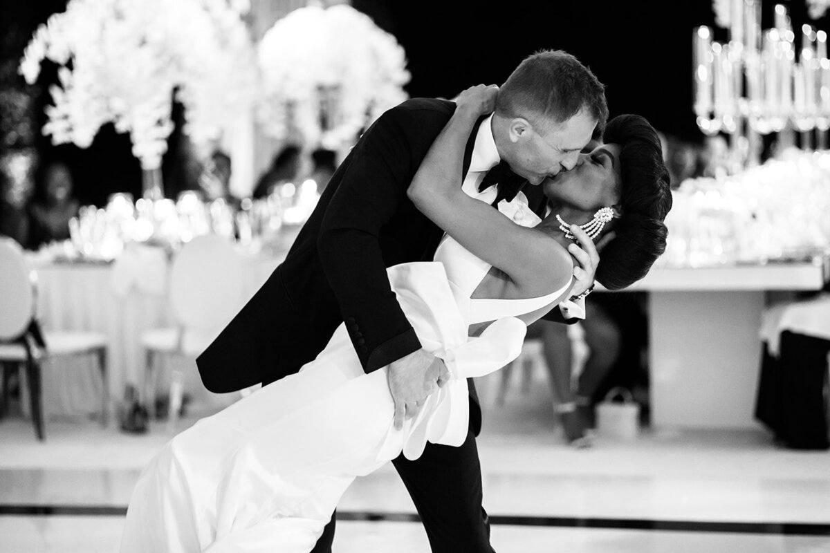 Bride and groom in a romantic dip during their dance, surrounded by guests.