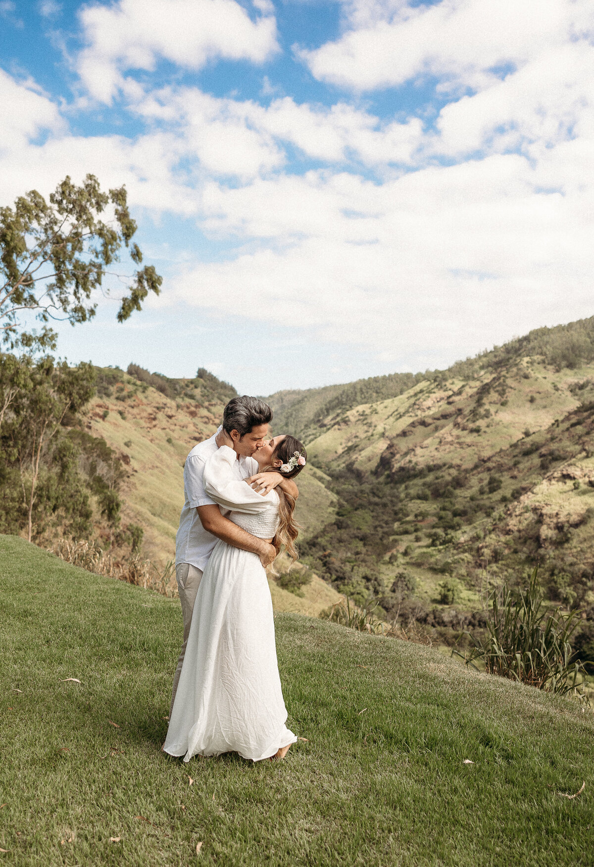 bride and groom kissing on a cliff in hawaii