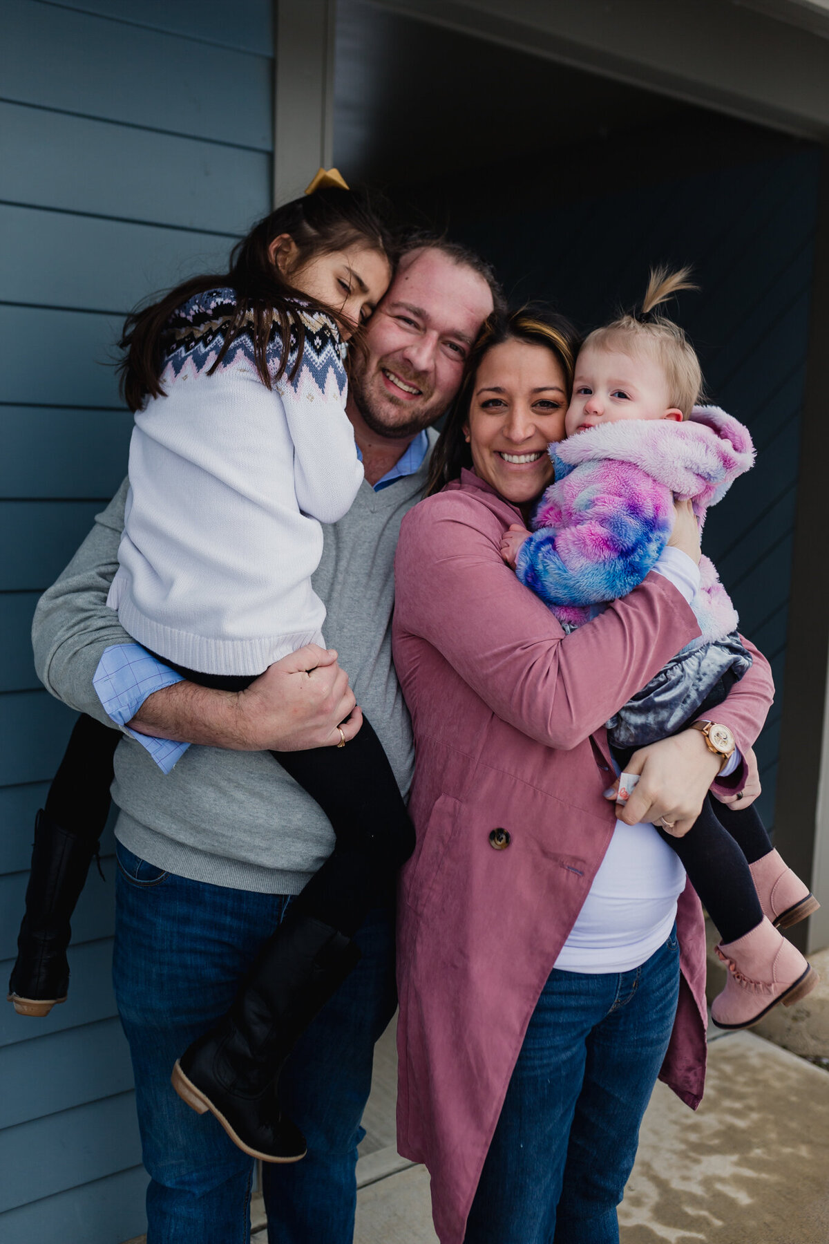 Pregnancy announcement photoshoot with mom, dad, and two young children.