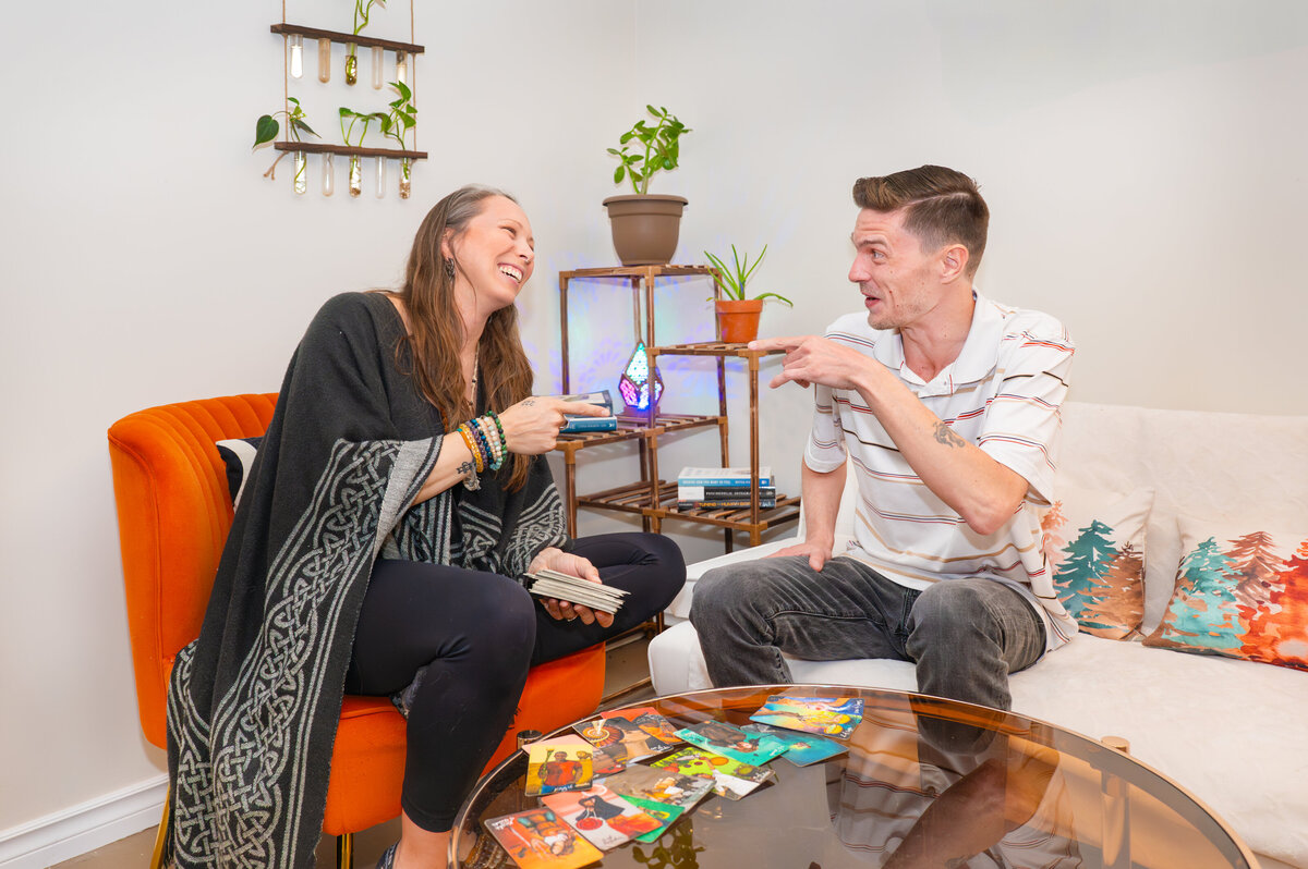Falen Reid, holistic healer, smiling and laughing with her tarot reading client