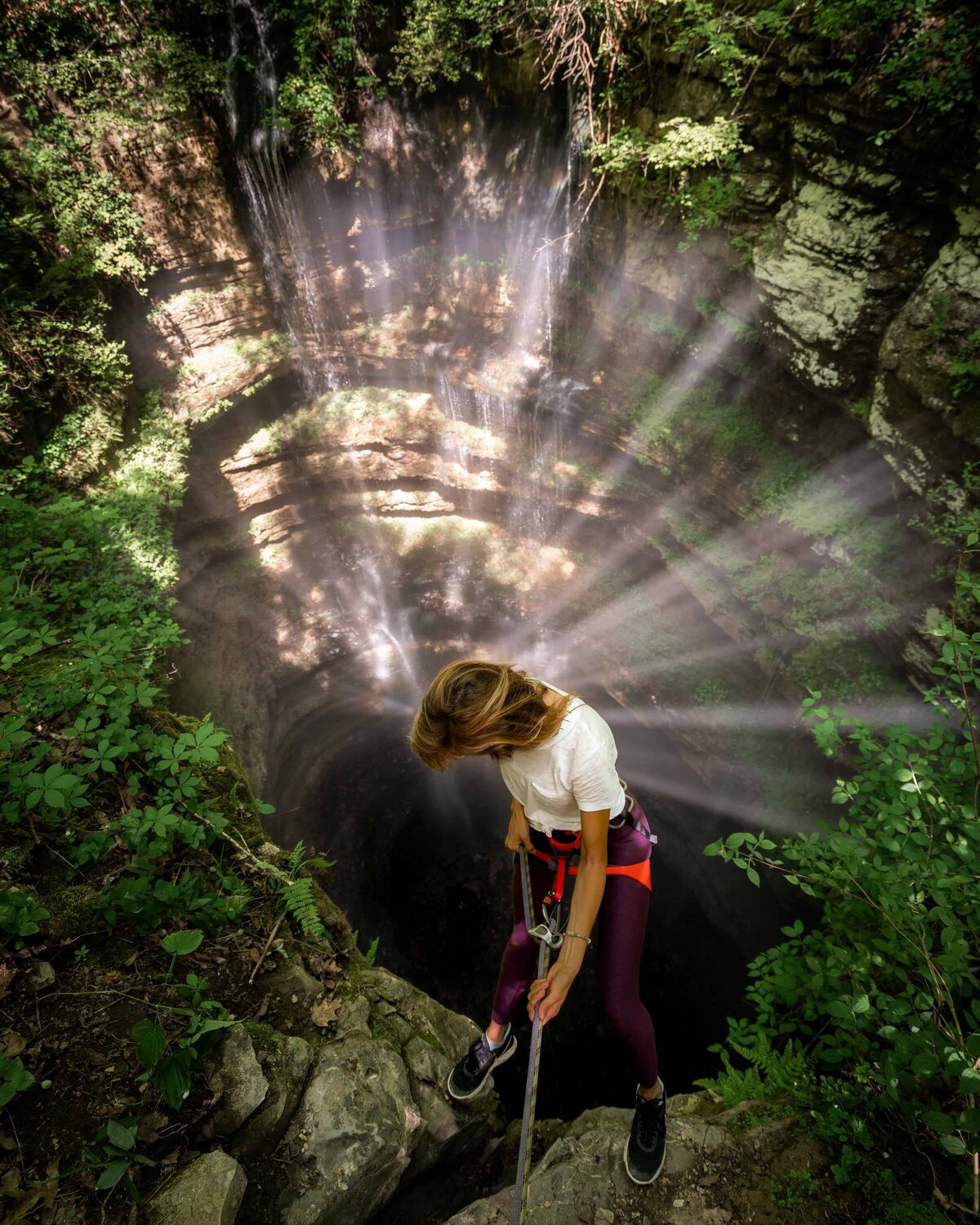 Woman holding onto rope going down into a canyon