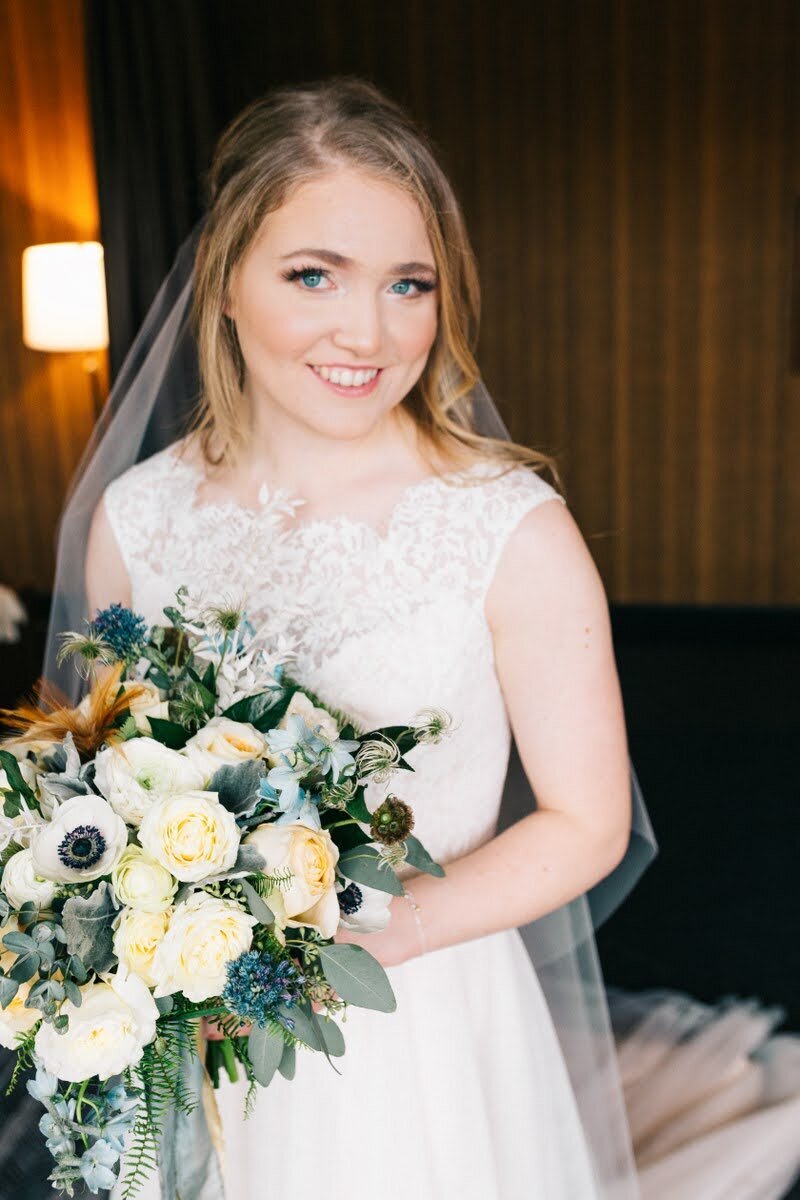 Bride holds her bouquet with shades of blue, white, and yellow.