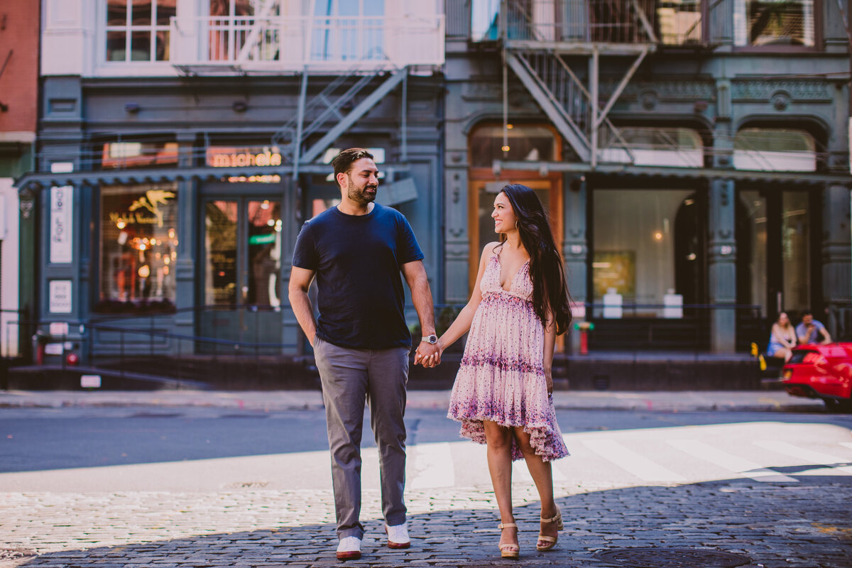 A couple walking together during their engagement session in soho on a cobblestone street in nyc